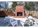Brick outdoor fireplace surrounded by comfortable seating and firewood storage in landscaped backyard at 139 W Paces Ferry Nw Rd, Atlanta, GA 30305