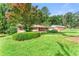 View of well-kept house featuring a lush green lawn, colorful flowering tree, and mature landscaping at 5666 Bob White Nw Cir, Lilburn, GA 30047
