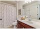 Cozy bathroom featuring cherry cabinet, toilet, shower curtain and decorative mirror at 5890 Vinyard Ln, Cumming, GA 30041