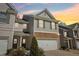 Townhome featuring stone accents on the facade and a two-car garage at sunset at 5890 Vinyard Ln, Cumming, GA 30041