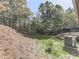 Grassy backyard area with a deck, wooded backdrop, and air conditioning unit at 1166 Upper Sweetwater Se Trl, White, GA 30184