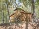 Wooden outbuilding amid lush trees, featuring a dark door with a striking geometric design at 1166 Upper Sweetwater Se Trl, White, GA 30184