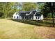 Exterior shot of a white farmhouse featuring a well-manicured lawn and mature trees at 1632 Oleander Sw Dr, Lilburn, GA 30047