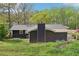 Rear exterior with dark siding, lush greenery and a glimpse of the carport at 2407 Ridgeway Dr, Doraville, GA 30360