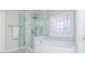 Bright bathroom with a glass-enclosed shower, soaking tub, and decorative privacy window at 2296 Valley Brook Ne Way, Atlanta, GA 30319