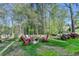 Inviting backyard fire pit with red Adirondack chairs nestled amongst mature trees and lush green lawn at 4230 Braden Nw Ln, Kennesaw, GA 30144