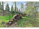 Lush backyard scene with stacked wood, a fire pit seating area, and a peaceful, green landscape at 4230 Braden Nw Ln, Kennesaw, GA 30144