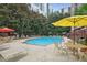Community pool surrounded by lounge chairs, tables, lush landscaping, and shade umbrellas at 1101 Juniper Ne St # 1511, Atlanta, GA 30309