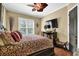 A cozy primary bedroom with a decorative ceiling fan, plush bedding, and a TV at 2450 Weber Heights Way, Buford, GA 30519