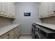 Well-appointed laundry room with wallpaper, front-loading washer/dryer, and TV at 290 Ardsley Ln, Alpharetta, GA 30005