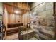 Modern sauna featuring wood paneling, a glass door, stone accented walls, and a tile shower bench at 290 Ardsley Ln, Alpharetta, GA 30005