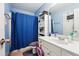 Bathroom features a white vanity, toilet and storage cabinet with a blue shower curtain at 3560 Glen Summit Ln, Snellville, GA 30039