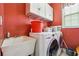 Laundry room with washer, dryer, utility sink and overhead cabinets, with red walls at 3560 Glen Summit Ln, Snellville, GA 30039