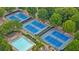 Aerial view of tennis courts and a swimming pool surrounded by lush greenery, offering a picturesque setting for recreation at 6730 Waterbury Way, Cumming, GA 30040
