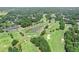 An aerial view of the golf course and clubhouse featuring lush green fairways, mature trees and a tranquil pond at 6730 Waterbury Way, Cumming, GA 30040