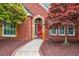 Charming brick home with a red door and colorful landscaping creates a welcoming entrance at 6730 Waterbury Way, Cumming, GA 30040