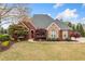 Charming brick home features manicured lawn, mature trees, and a paved walkway leading to the entrance at 6730 Waterbury Way, Cumming, GA 30040