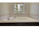Corner soaking tub with tile surround, set under a window for natural light at 806 Jefferson Sw Ct, Conyers, GA 30094