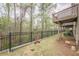 Backyard of townhouse has grassy area with black fence and wooded area at 2705 Maple Park Pl # 29, Cumming, GA 30041