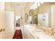 Bright bathroom featuring double sinks, granite countertop, gold fixtures, and doorway with views to the staircase at 3022 Loridan Se Way, Atlanta, GA 30339