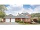 Rear exterior view of a brick home featuring a three-car garage, landscaping, and a gray roof at 3022 Loridan Se Way, Atlanta, GA 30339