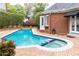 Backyard with a brick patio, pool, and spa, as well as a red brick facade with white doors and windows at 3022 Loridan Se Way, Atlanta, GA 30339