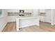 Bright white kitchen with a large island, stainless steel appliances, and wood flooring at 7200 Brushwood Bend - Lot 117, Lithonia, GA 30058