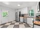 Well-lit kitchen with white cabinets, stainless steel appliances, and a black and white tiled floor at 573 Lyle Se Dr, Marietta, GA 30067