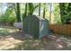 Outdoor storage shed nestled amidst mature trees and a wooden fence providing ample storage at 573 Lyle Se Dr, Marietta, GA 30067