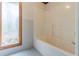A tiled bathroom with a bathtub, window view, and neutral-colored walls at 452 Hightower Ridge Rd, Covington, GA 30014