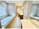 Bathroom with a large window, double vanity, and a soaking tub by the window at 512 Clearwater Dr, Mcdonough, GA 30252