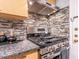 Close up view of the stainless steel range and oven with mosaic tile backsplash and granite countertops at 6851 Roswell Rd # A-12, Atlanta, GA 30328