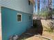 Side view of home featuring light blue siding, stucco and two windows, next to a fenced yard with trees at 6675 Hidden Brook Trl, Atlanta, GA 30349