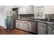 Modern kitchen features stainless steel appliances, tile backsplash, gray cabinets, and hardwood floors at 8207 Fairview Blf, Alpharetta, GA 30022