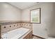 Elegant bathroom featuring a soaking tub with tiled surround and a window with plantation shutters at 3100 Queens Ne Walk, Atlanta, GA 30345