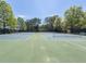 View of the community tennis courts, featuring green and blue hard surface and surrounding trees at 5650 Upper Creek Ct, Suwanee, GA 30024