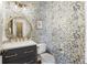 Charming powder room featuring patterned wallpaper, a round mirror, elegant fixtures, and vanity with storage at 11265 Musette Cir, Alpharetta, GA 30009