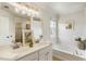 Bright bathroom featuring double sinks, tub, stylish lighting, and a neutral color palette at 11265 Musette Cir, Alpharetta, GA 30009