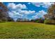 An expansive field dotted with trees under a clear blue sky, offering endless possibilities for recreation and agriculture at 610 Loth Wages Rd, Dacula, GA 30019