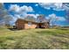 Brick single-story home with an enclosed patio and large yard with mature trees and a partly cloudy sky at 610 Loth Wages Rd, Dacula, GA 30019