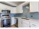Updated kitchen with white cabinetry, stainless steel appliances, undermount sink, and attractive blue backsplash at 2161 Peachtree Ne Rd # 907, Atlanta, GA 30309