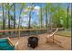 Backyard gravel area featuring a fire pit and chairs, surrounded by trees and a fence at 5485 Woodrun Ln, Johns Creek, GA 30005