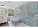 Modern main bathroom features blue tile, glass shower, and soaking tub with backyard view at 5485 Woodrun Ln, Johns Creek, GA 30005