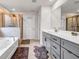 Spa-like bathroom with a soaking tub, walk-in shower, and a double vanity with gray cabinets at 787 Milo Bay Street, Loganville, GA 30052