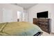 Bedroom featuring a large bed with a green comforter, a dresser with a TV, and a carpeted floor at 787 Milo Bay Street, Loganville, GA 30052
