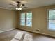 Spacious bedroom with large windows overlooking a landscaped yard with carpet and ceiling fan at 908 Chippendale Ln, Norcross, GA 30093