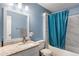 Bright bathroom features a granite countertop, vanity, and shower with blue shower curtain at 7275 Oswego Trl, Riverdale, GA 30296
