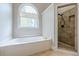 Modern bathroom featuring a garden tub with a large window and a tile shower at 7405 Richmond Way, Cumming, GA 30040