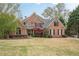 Beautiful two-story brick home featuring a manicured lawn and mature trees at 7405 Richmond Way, Cumming, GA 30040