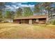 Backyard with brown grass, trees, and a wood-paneled house at 2140 Teri Ln, Conyers, GA 30013
